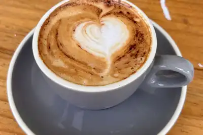 A cappuccino with a heart in the foam, in a grey cup on a wooden table