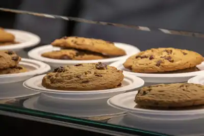 Chocolate chip cookies on small plates in a glass counter