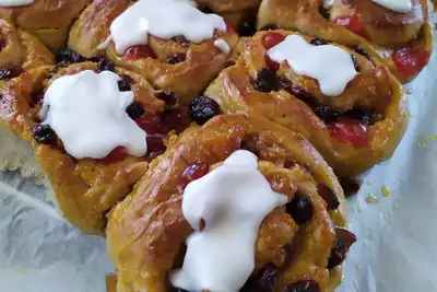 Fruit buns with white icing on baking paper