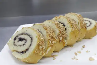 Slices of a jam-filled sponge roll topped with chopped nuts