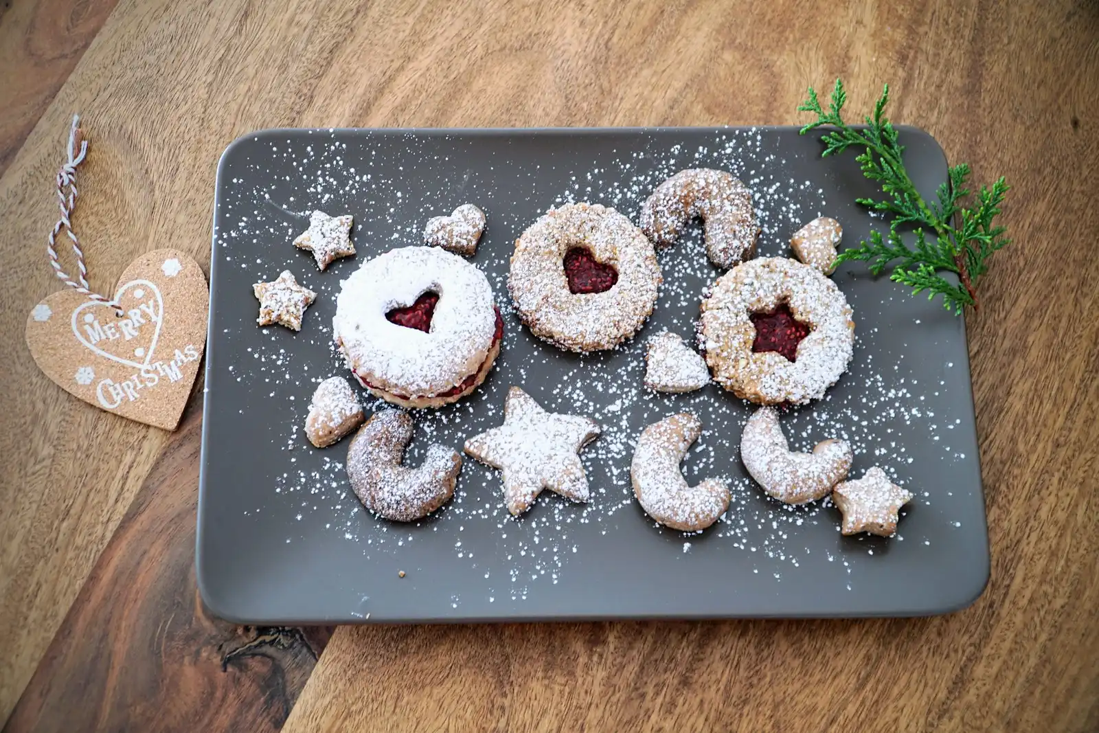 Jam-filled cookies dusted with icing sugar on a grey plate
