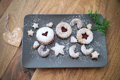 Jam-filled cookies dusted with icing sugar on a grey plate