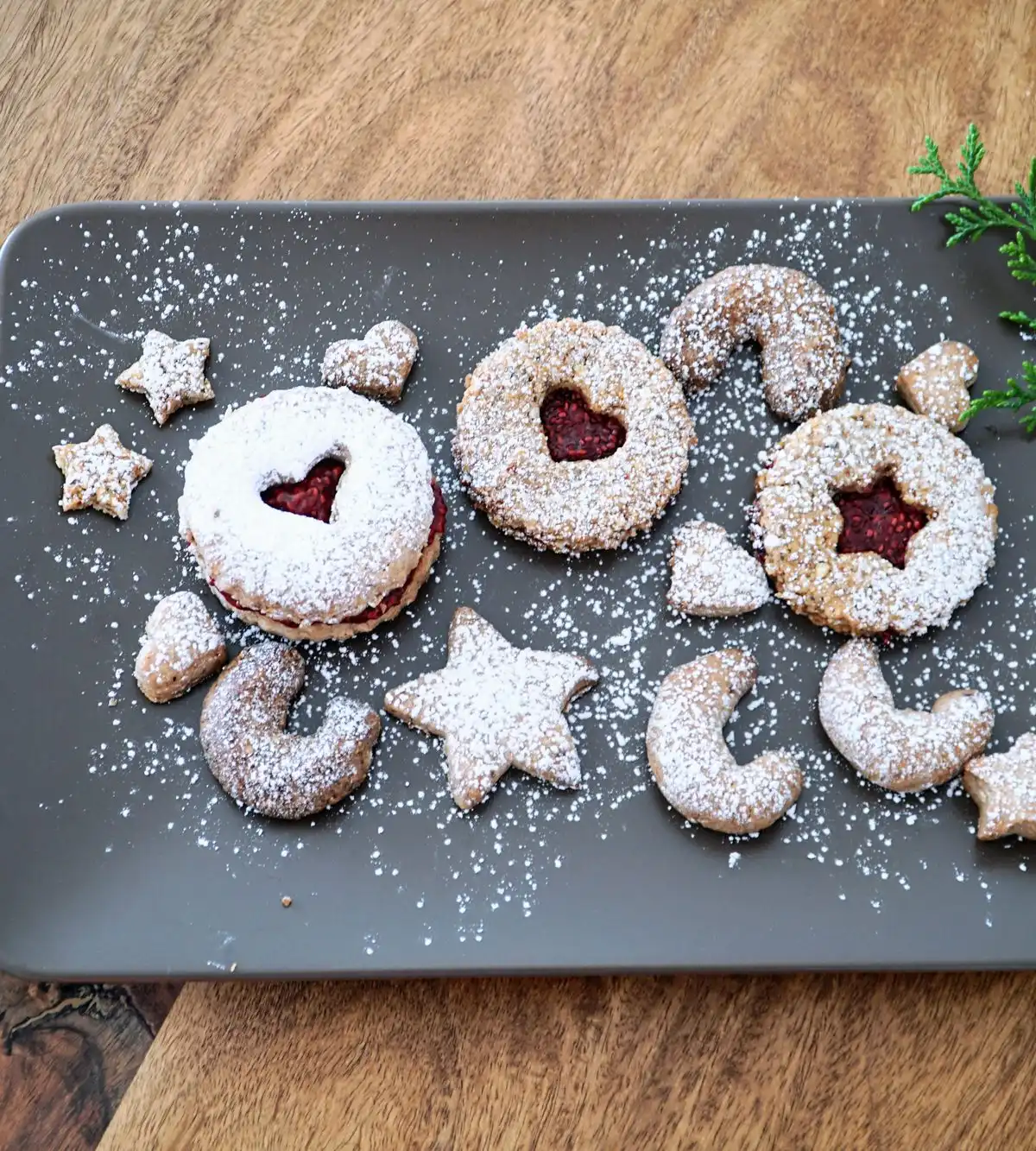 Jam-filled cookies dusted with icing sugar on a grey plate