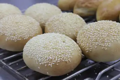 Sesame-topped bread buns on a cooling rack