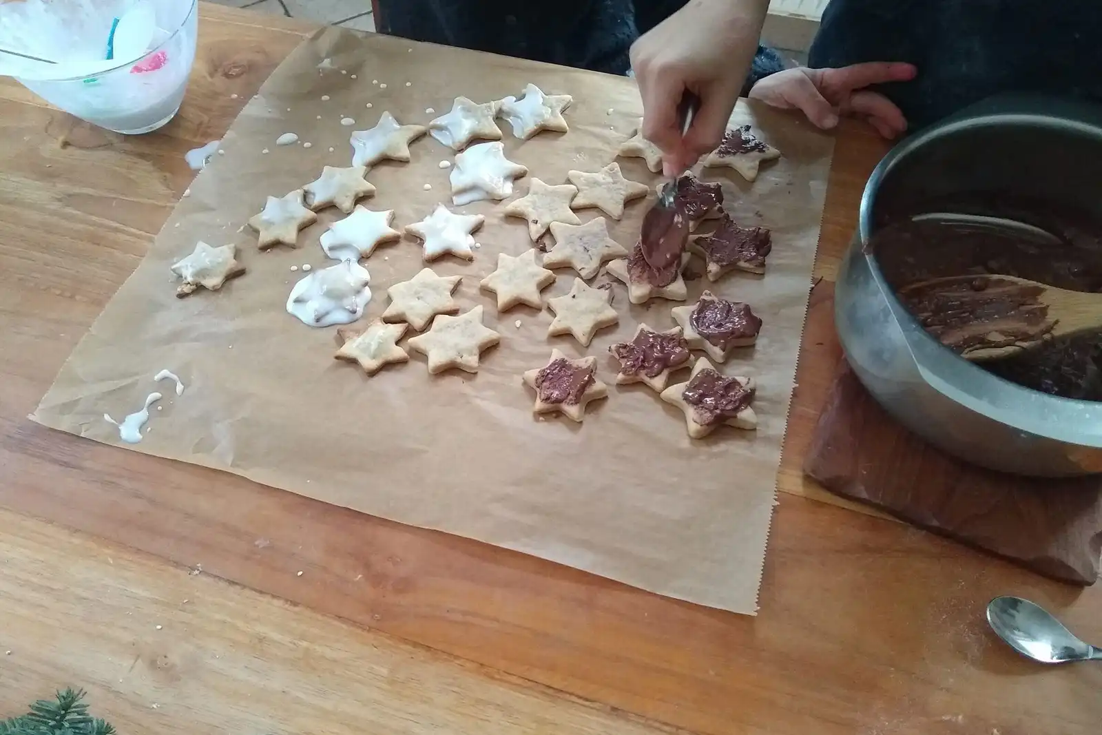 Hands icing star-shaped cookies on baking paper