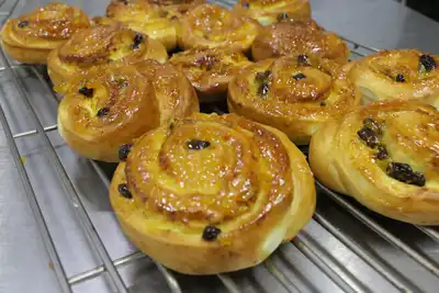 Glazed raisin swirl buns cooling on a wire rack